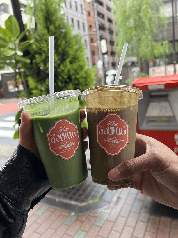 Two iced matcha drinks, cheers outdoors